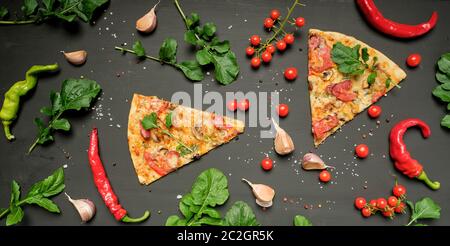 Dreieckige Stück Pizza mit Pilzen, geräucherte Wurst, Tomaten und Käse, schwarzer Hintergrund, flach Stockfoto