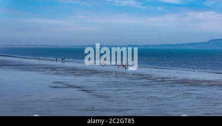 Am Rande des Wassers am Dollymount Strand in Dublin, Irland, versammelten sich Menschen. Stockfoto