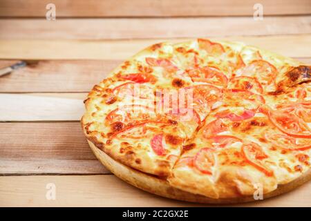 Mittlere Pizza mit Tomaten auf einer hölzernen Fach Stockfoto