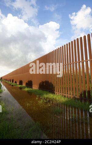 Cameron County Texas USA, 23. September 2014: Die Metallgrenzmauer verläuft mehrere Kilometer durch ein ländliches Gebiet östlich von Brownsville, um den Strom illegaler Einwanderer, die den Rio Grande River von Mexiko aus in die Vereinigten Staaten überqueren, zu kontrollieren. Rancher mit Grundstücken auf der Südseite der Mauer müssen durch riesige Metalltore mit Tastenfeld eintreten. ©Bob Daemmrich Stockfoto