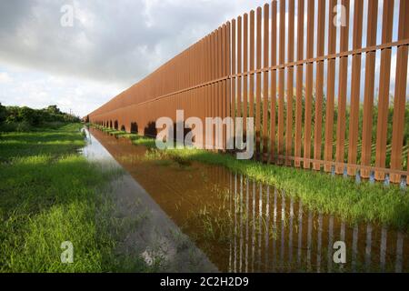 Grenzmauer in Süd-Texas - die Grenzmauer verläuft mehrere Meilen durch eine ländliche Gegend östlich von Brownsville, Texas, um den Fluss illegaler Einwanderer zu kontrollieren, die den Rio Grande Fluss von Mexiko aus überqueren. Rancher mit Grundstück an der Südseite der Wand müssen durch riesige Metalltore mit Tastenfeld Eingang betreten. 23. September 2014 © Bob Daemmrich Stockfoto