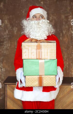 Santa Claus insgeheim anbringen Geschenkboxen unter dem Weihnachtsbaum Stockfoto
