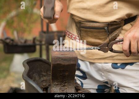 Schmied arbeitet an Metall auf einem Amboss in der Schmiede Stockfoto