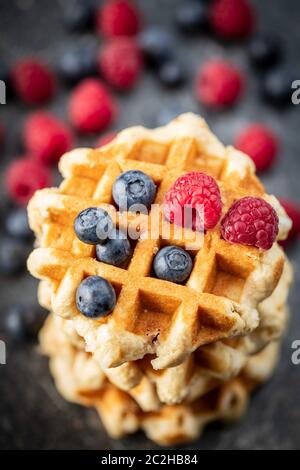Waffeln mit Heidelbeeren und Himbeeren auf alten Küchentisch. Stockfoto