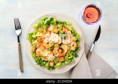 Garnelen Caesar Salat mit Parmesan Käse, Croutons und Salat, Schuß von der Oberseite mit einem Glas Rose Wein Stockfoto