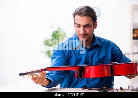 Junger Mann Reparatur der Gitarre Stockfoto