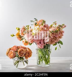 Ein Hochzeitsstrauß aus rosa und orange Lisianthus, antirrhinum und verschiedenen Sorten von Eukalyptus in einer Glasvase auf dem Küchentisch. Leerzeichen für Text Stockfoto