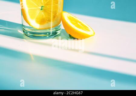 Gelbe Lemmonscheiben in einem Glas auf dem Tisch. Hartes Sonnenlicht und Schatten. Stockfoto