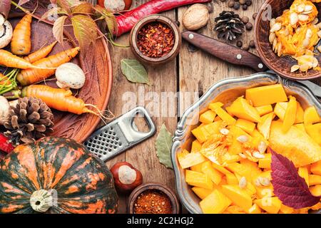 Kürbis schnitt in einem Stück und Lebensmittelzutaten. Herbst vegetarisches Essen auf hölzernen Hintergrund Stockfoto