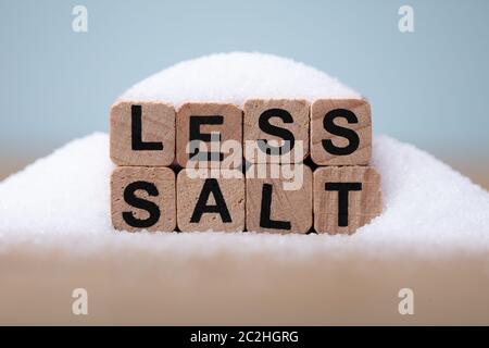 Weniger Salz Wort bedeckt mit Salz auf hölzernen Schreibtisch Stockfoto