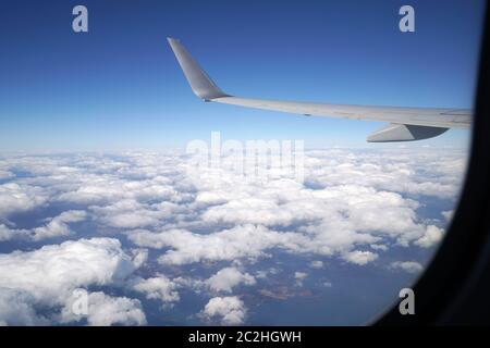 Flügel eines Flugzeugs fliegen über den Wolken, aus dem Fenster des Flugzeugs Stockfoto