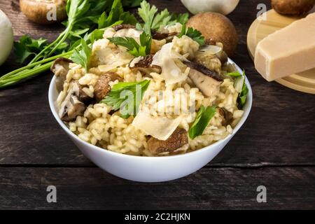 Risotto ai Funghi, Pilze Reis mit Zutaten auf einem dunklen Holzmöbeln im Landhausstil Hintergrund Stockfoto