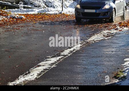 Unfallgefahr für Autos durch nasse Blätter und Schnee auf der Straße Stockfoto