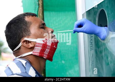 Guwahati, Assam, Indien. Juni 2020. Hinter einem Plexiglas-Sieb sammelt ein Sanitäter Testproben von einem Mann für den COVID-19-Abstrichtest während der laufenden landesweiten Sperre in Dispur in Guwahati. Kredit: David Talukdar/ZUMA Wire/Alamy Live Nachrichten Stockfoto