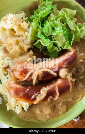 Würstchen mit Kartoffelbrei. Gebackene Wurst im Onion gravy mit Kartoffelpüree und Rotkohl serviert. Stockfoto