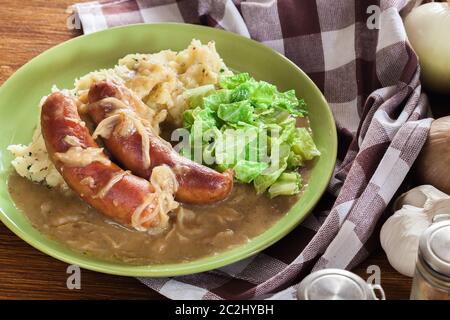 Würstchen mit Kartoffelbrei. Gebackene Wurst im Onion gravy mit Kartoffelpüree und Rotkohl serviert. Stockfoto