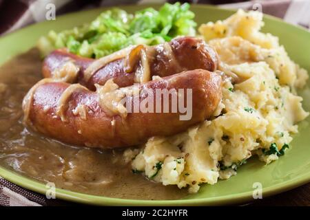 Würstchen mit Kartoffelbrei. Gebackene Wurst im Onion gravy mit Kartoffelpüree und Rotkohl serviert. Stockfoto