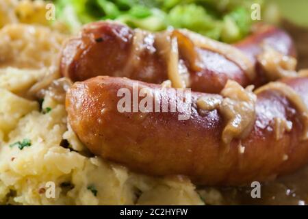 Würstchen mit Kartoffelbrei. Gebackene Wurst im Onion gravy mit Kartoffelpüree und Rotkohl serviert. Stockfoto