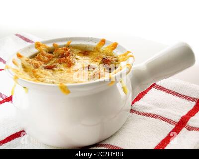 Zwiebelsuppe in einer weißen Schüssel. Ein klassisches französisches Gericht, das hauptsächlich aus langsam gekochten Zwiebeln in einer Rinderbrühe und gebratenem Käse besteht. Stockfoto