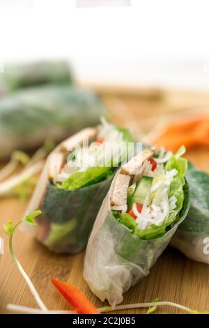 Frische vietnamesische Frühlingsrollen, ideal als gesunde Vorspeise mit Erdnussbutter-Sauce zum Eintauchen. Das Essen wird auf ein Holzschneidebrett gelegt. Stockfoto