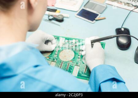 Techniker, der Komponenten auf eine Leiterplatte im Elektronikwerk lötet Stockfoto