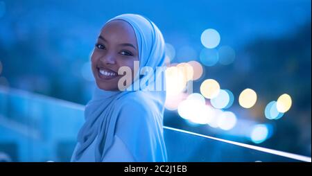 Afrikanische moderne muslimische Frau in der Nacht auf dem Balkon Stockfoto