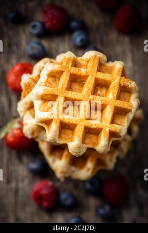 Waffeln mit Heidelbeeren und Himbeeren auf alten Holztisch. Stockfoto