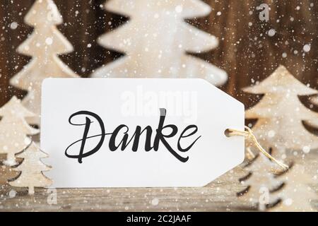 Etikett mit deutschem Text Danke, Danke. Weiß Holz- Weihnachten Baum als Dekoration. Braun Holz- Hintergrund mit Schnee Stockfoto