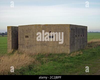 Zweiter Betonkasten im Weltkrieg an der Ostküste von Yorkshire, England. Hinterer Eingang und Schlupflöcher sichtbar. Umgeben von Gras. Blauer Himmel mit Weiß Stockfoto