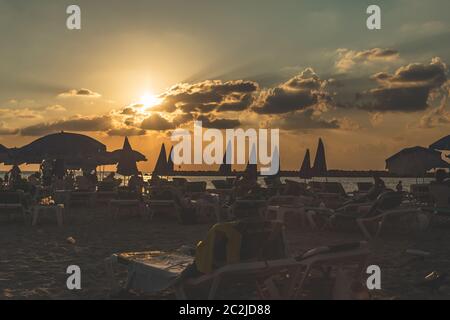 Menschen, die am Abend kurz vor Sonnenuntergang auf Sonnenliegen am Strand von Tel Aviv liegen Stockfoto