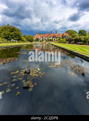 Blick auf das ikonische, historische Laborgebäude am Jellicoe Canal unter schwerem grauen Himmel im RHS Wisley Garden in Surrey, Südostengland Stockfoto