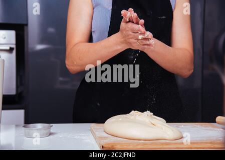 Hände von Baker Frau weiblich die Besprengung klatschen Mehl Teig auf Tisch Stockfoto