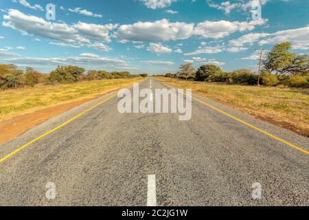 Endlose Straße in Botswana, sonnigen Tag mit blauem Himmel, Afrika Stockfoto