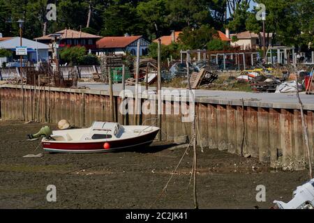 Ein kleines Motorboot liegt bei Ebbe im Schlamm im Hafen von Piraillan, im Becken von Arcachon, Frankreich Stockfoto