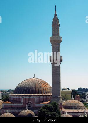 Kuppeln und Minarett der suleiman Moschee in der Altstadt von rhodos mit einem hohen Minarett vor einem blauen, sonnenbeschienenen Himmel Stockfoto