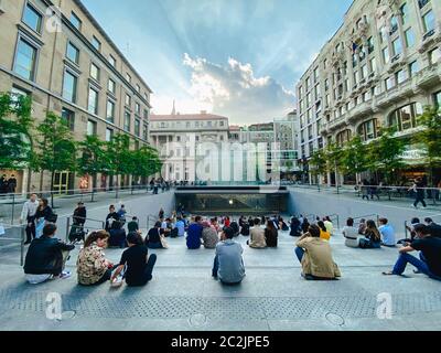 25. September 2019 Italien. Mailand. Viele Leute sitzen auf Stufen in der Nähe des Apfelladens in Mailand. Auf der Treppe, bewundern Sie die Krys Stockfoto