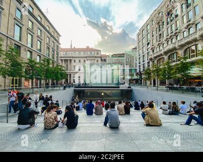 25. September 2019 Italien. Mailand. Viele Leute sitzen auf Stufen in der Nähe des Apfelladens in Mailand. Auf der Treppe, bewundern Sie die Krys Stockfoto