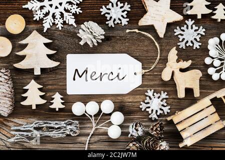 Eine White Label mit französischen Text Merci bedeutet. Vielen Dank. Rahmen von Weihnachten Dekoration wie Baum, Schlitten-, Stern- und Tannenzapfen. Holz- Hintergrund Stockfoto