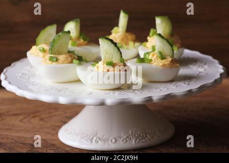 Würzige Russische Eier garniert mit Gurke und Lauch auf weiße Platte. Stockfoto