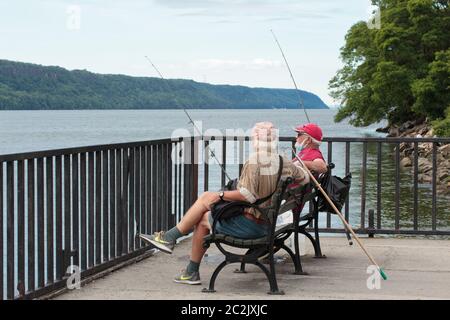 Zwei alte Männer fischen vom Dock an der Dyckman Marina am Hudson River in Upper Manhattan mit der New Jersey Küste im Hintergrund Stockfoto