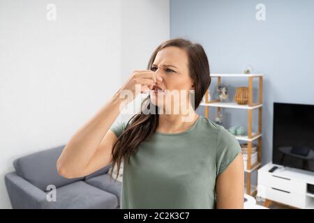 Frau, die Ihre Nase von schlechten Geruch im Haus Stockfoto