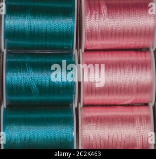 Ausschnitt Textur closeup auf Spulen von farbigen Nähgarne Blau und Rosa. Stockfoto