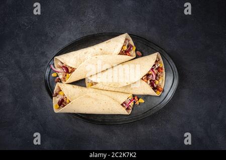 Burrito Sandwich Wraps, von oben auf schwarzem Hintergrund geschossen. Tortillas gefüllt mit Hackfleisch, Reis, Bohnen, Zwiebeln, ein Stockfoto