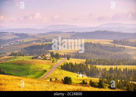 Bergstraße bei Sonnenuntergang im Sommer. Kurvige Asphaltstraße auf den Hügeln. Pieniny und Beskidy Range Stockfoto