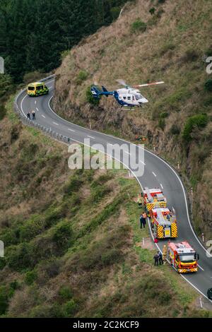 Ein Rettungshubschrauber senkt eine mit Extragungsausrüstung angehäuft auf die Straße neben wartenden Rettungsdiensten Stockfoto