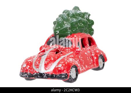 Weihnachtsschmuck Hintergrund. Nahaufnahme eines schneebedeckten rotes Auto Spielzeug mit grünen Tannen auf dem Dach auf einem weißen Hintergrund. Saisonale Desig Stockfoto