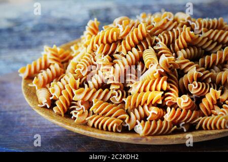 Vollkorn Fusilli in einer Platte. Integral Pasta über einen hölzernen Tisch. Stockfoto