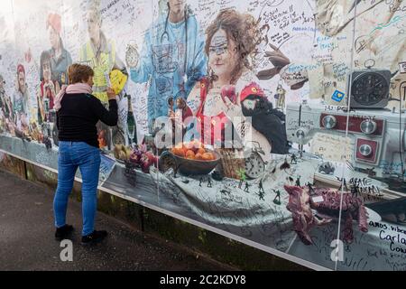 Frau, die das Wandbild der Friedensmauer in Belfast, Nordirland, Großbritannien, Europa unterzeichnet hat Stockfoto