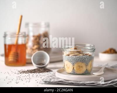 Gesundes Frühstück Konzept und Idee - chia Pudding mit organischen Banane und Biene Blütenstaub. Glas Glas Chia puding auf weißem Marmortisch. Kopieren Sie Platz für Text Stockfoto