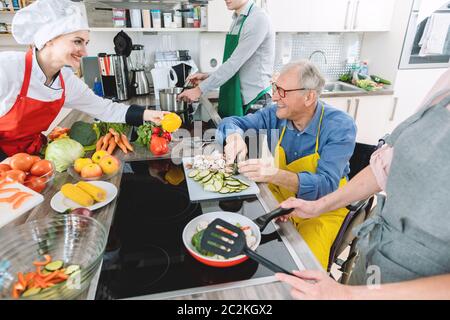 Gruppe von Männern und Frauen lernen Kochen in der Ausbildung Küche mit Ernährungsberater Stockfoto